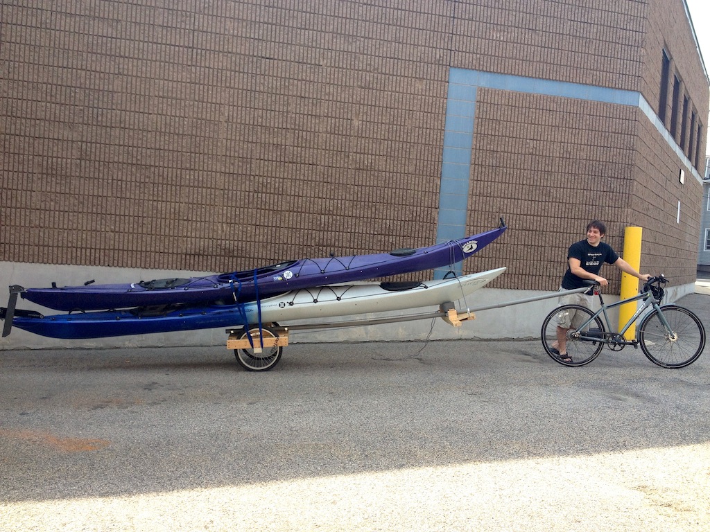 Two sea kayaks being towed by a bicycle